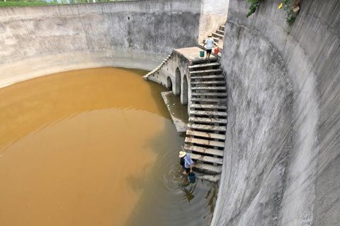 7月31日，湖北省郧县徐家村村民从基本干涸的池塘里挑水。（图片来源于新华网）